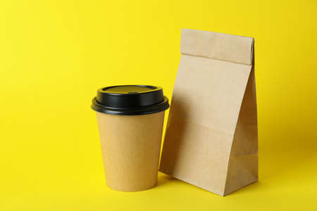 Paper cup and paper bag on yellow background