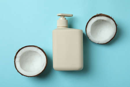 Soap bottle and coconut on blue background