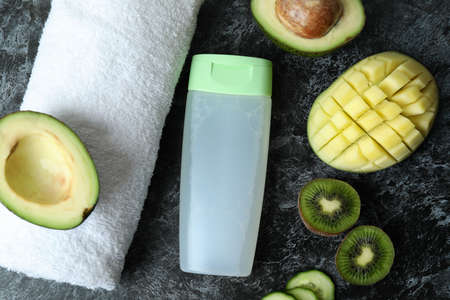 Natural shower gel, towel and ingredients on black smokey table