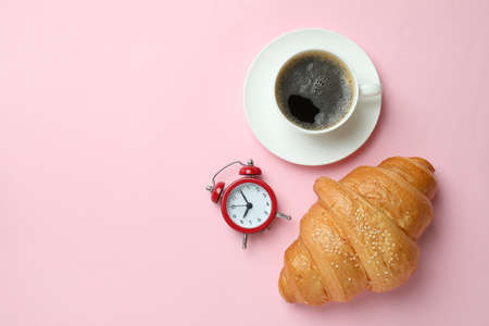 Croissant, coffee and alarm clock on pink backgroundの写真素材