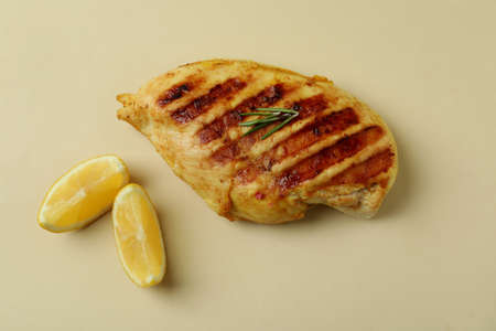 Grilled chicken meat and lemon on beige backgroundの写真素材