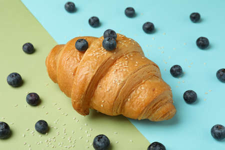 Croissant and blueberry on two tone background