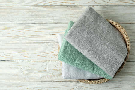 Basket with clean towels on white wooden table