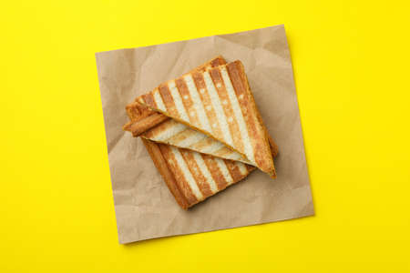 Paper with grilled sandwiches on yellow background