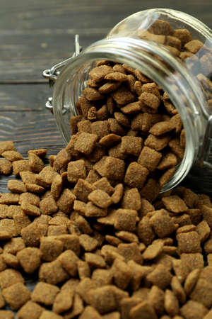 Glass jar with pet feed on wooden background