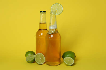 Bottles of beer and limes on yellow backgroundの写真素材