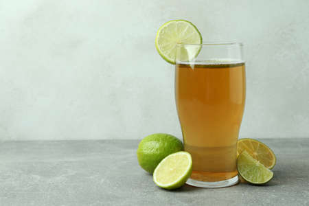 Glass of beer and limes against white textured backgroundの写真素材