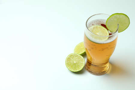 Glass of beer with lime on white background