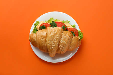Plate with croissant sandwich on orange backgroundの写真素材