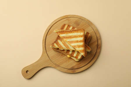 Board with grilled sandwiches on beige backgroundの写真素材