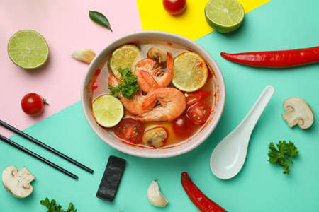 Concept of tasty eating with Tom yum soup on multicolor background