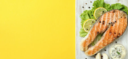 Concept of tasty eating with grilled salmon on yellow backgroundの写真素材