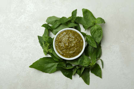 Bowl of Pesto sauce and basil on white textured backgroundの写真素材