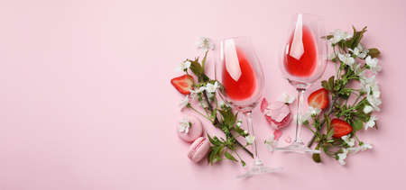 Wine, macaroons, strawberry and flowers on pink backgroundの写真素材