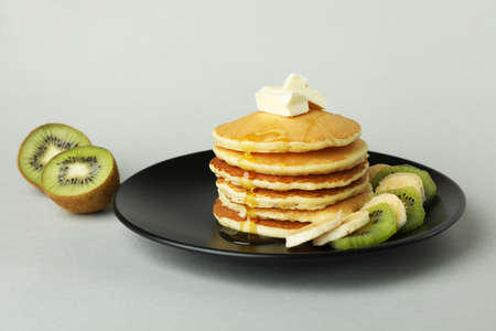 Plate with delicious pancakes and kiwi on gray backgroundの写真素材
