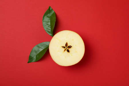 Apple slice with leaves on red background