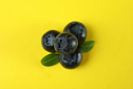 Fresh blueberry with leaves on yellow backgroundの写真素材
