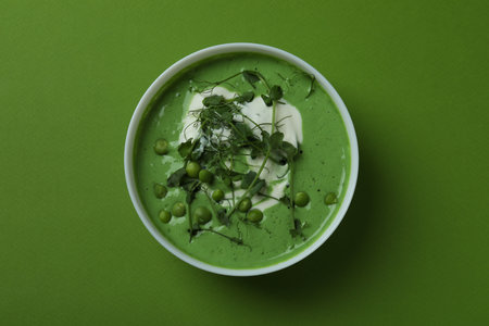 Bowl of pea soup on green background