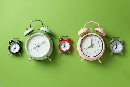 Different multicolor alarm clocks on green backgroundの写真素材
