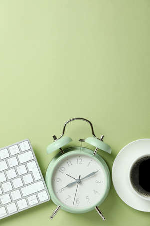 Workplace concept with alarm clock on green backgroundの写真素材