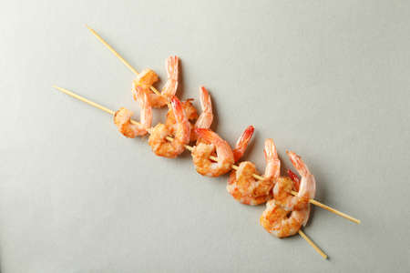 Tasty grilled shrimps skewers on gray background