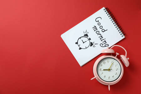 Notebook with Good morning and alarm clock on red background
