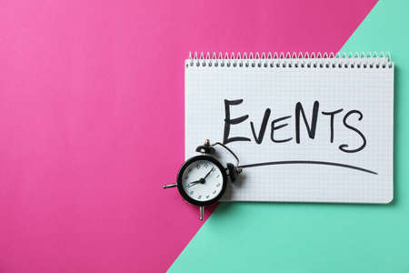 Notebook with Events and alarm clock on two tone backgroundの写真素材