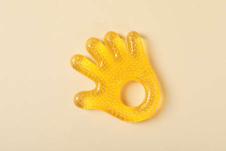 Baby rattle in the shape of a palm on a beige background