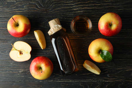 Homemade apple vinegar and ingredients on wooden table