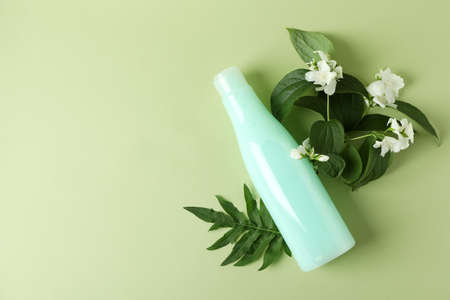 Blank bottle of shampoo and flowers on green backgroundの写真素材