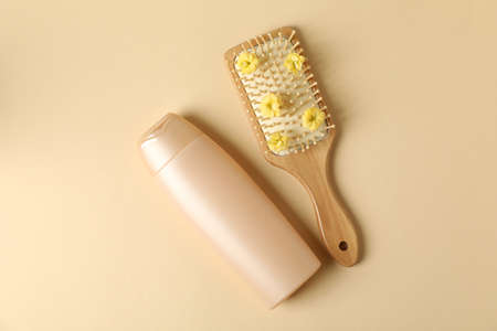 Blank bottle of shampoo and hair brush on beige background