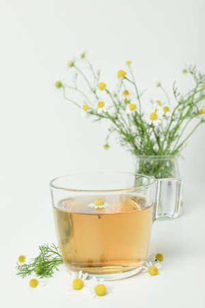 Cup of chamomile tea and ingredients on white tableの写真素材