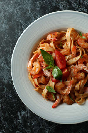 Plate of shrimp pasta on black smokey background