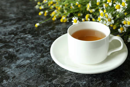 Cup of chamomile tea on black smokey tableの写真素材