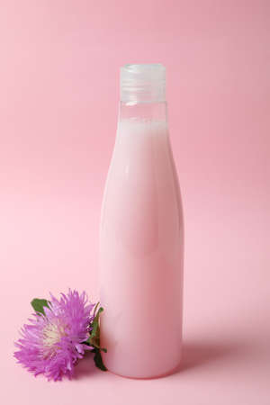 Blank bottle of shampoo and flower on pink backgroundの写真素材