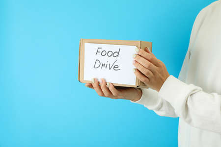 Woman holds food drive box on blue background