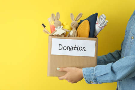 Woman holds donation box on yellow backgroundの写真素材