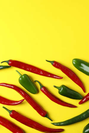 Red and green hot peppers on yellow background