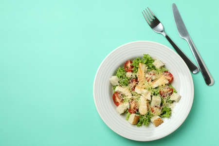 Plate with Caesar salad on mint backgroundの写真素材