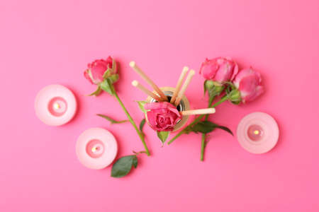 Diffuser, candles and roses on pink background