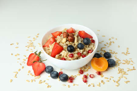 Bowl of oatmeal and ingredients on white background