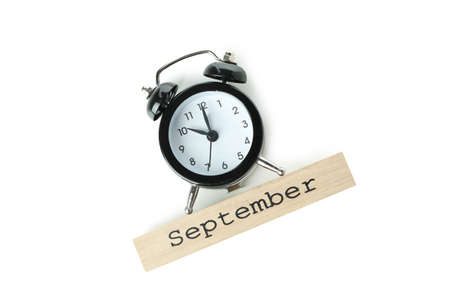 Alarm clock and wooden block with text September isolated on white background