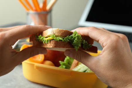 Workplace eating with female hands hold sandwich, close upの写真素材