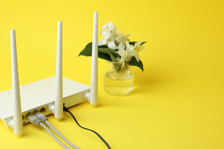 Wi-Fi router and flowers on yellow background