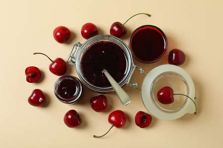 Cherry jam and ingredients on beige background