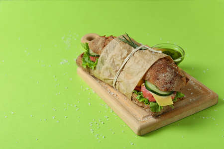Board with ciabatta sandwich, sauce and salt on green backgroundの写真素材