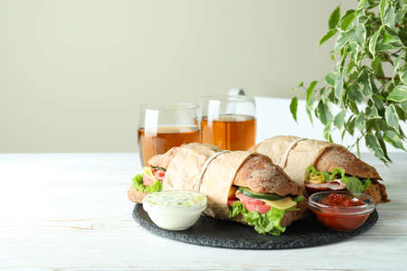 Concept of tasty eating with ciabatta sandwiches on white wooden tableの写真素材