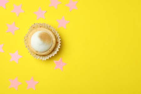 Lemon cupcake and pink stars on yellow background