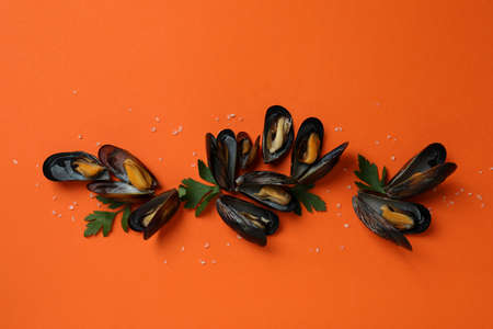 Fresh mussels on orange background, top view