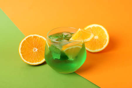 Glass of citrus cocktail and ingredients on two tone background